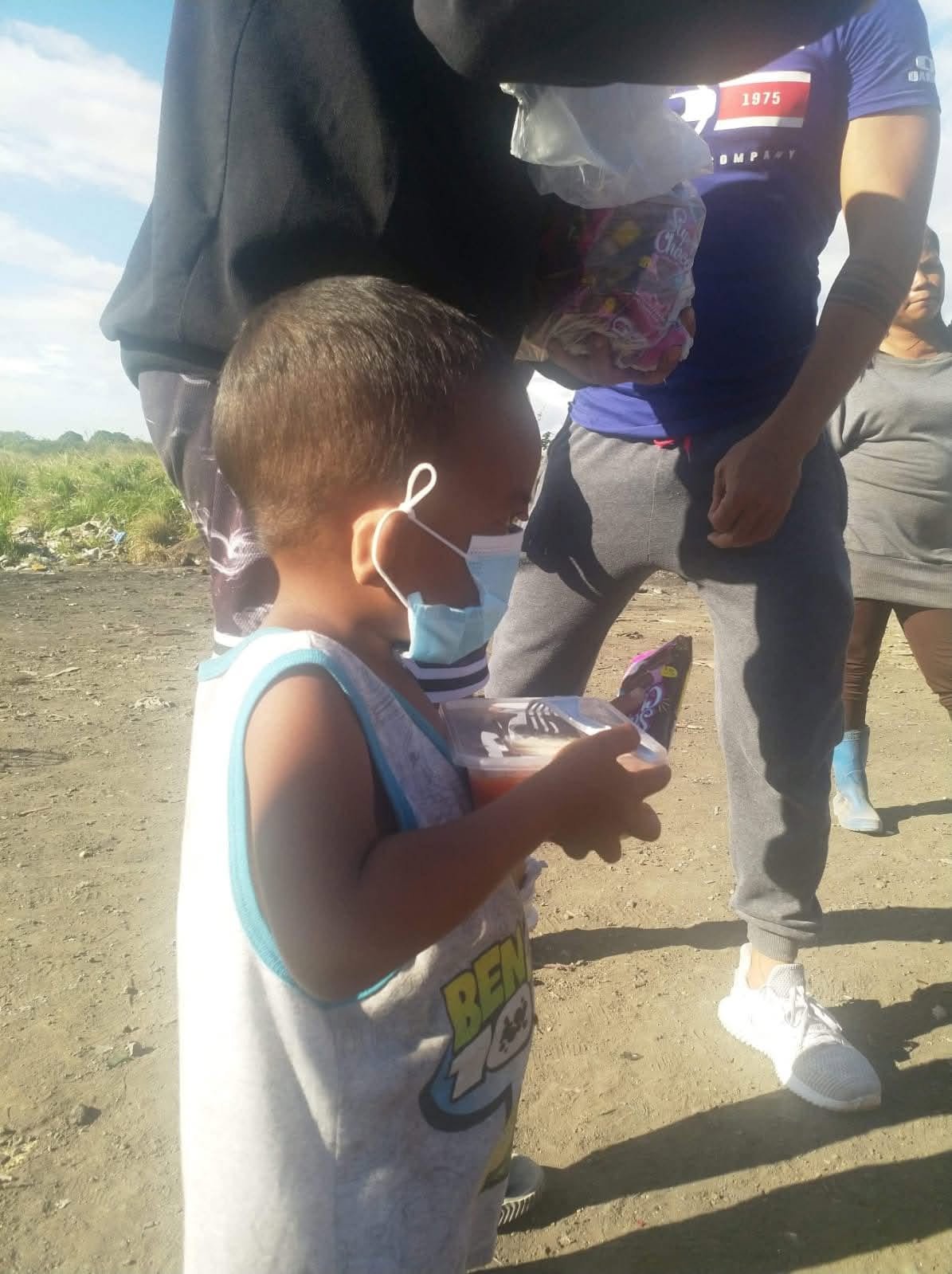 A child standing with adults at an outdoor activity
